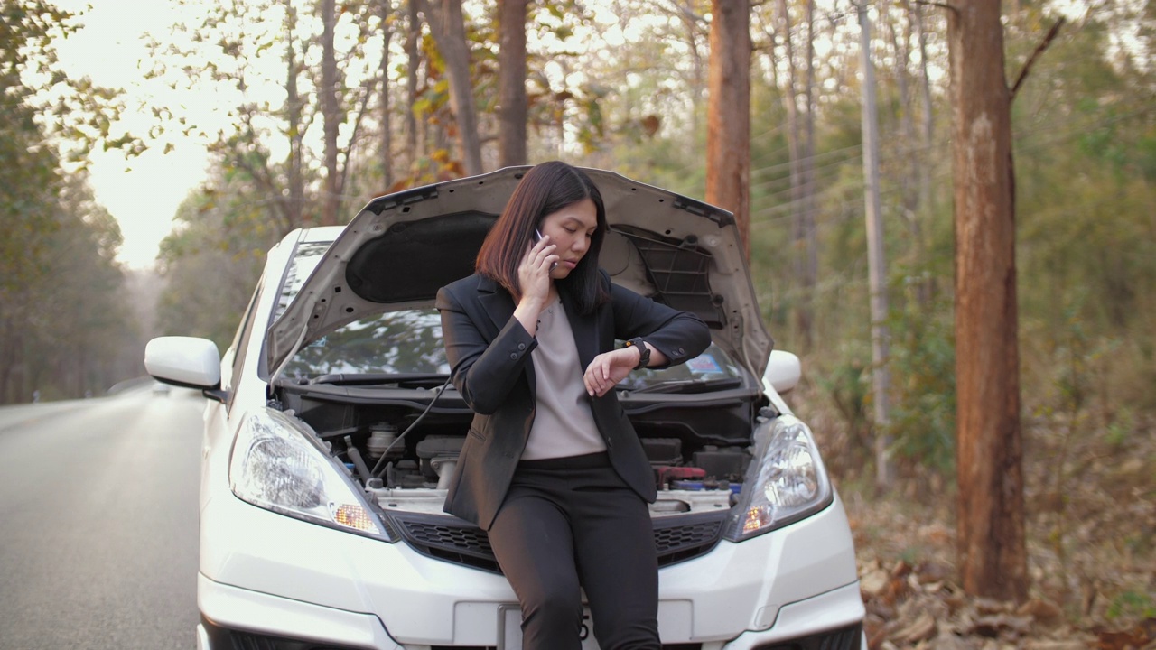 一名亚洲妇女打电话要求维修车辆在路上抛锚视频素材