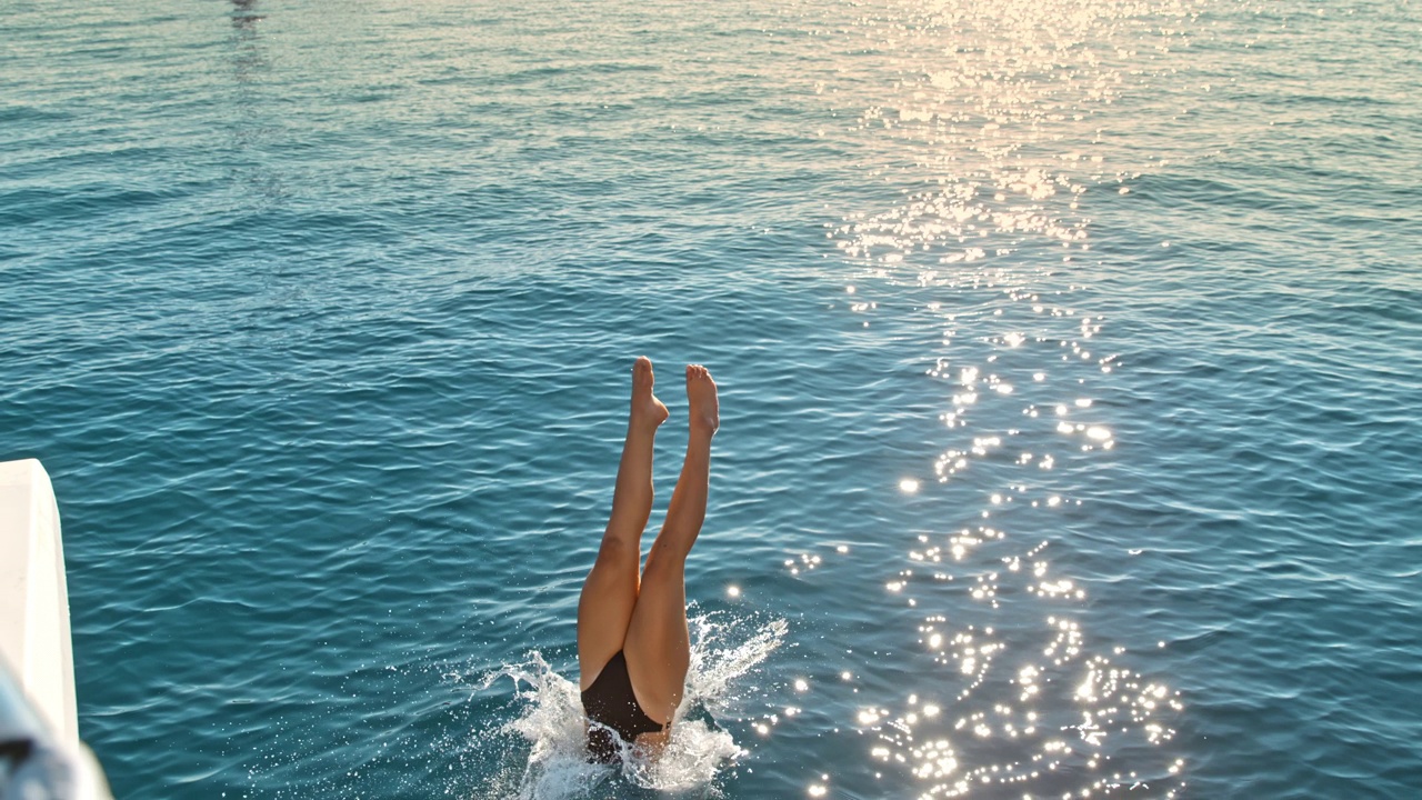 一名年轻女子从帆船上跳入大海视频素材