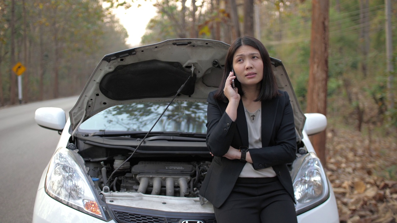 一名亚洲妇女打电话要求维修车辆在路上抛锚视频素材