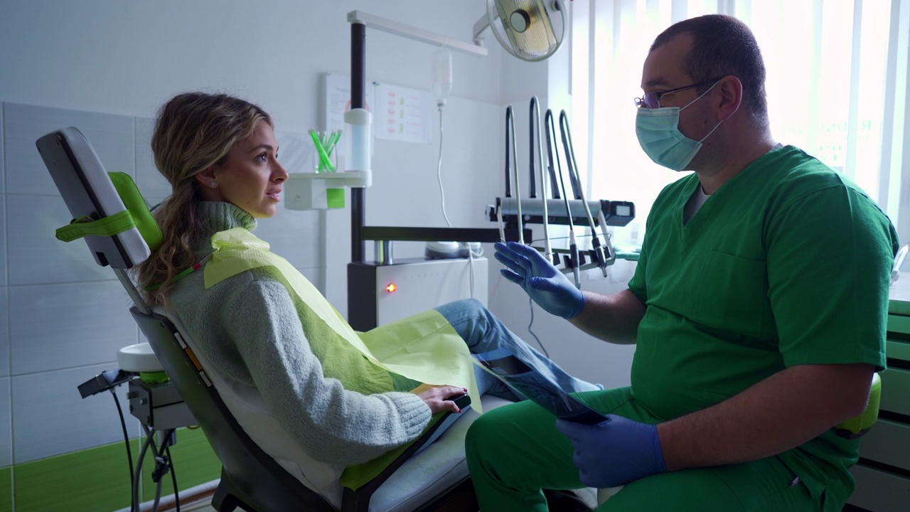 在检查期间，牙医与一位女性患者谈论治疗方案视频素材
