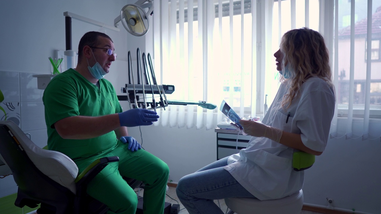 在牙科诊所，牙医一起观察病人的牙科x光图像视频素材