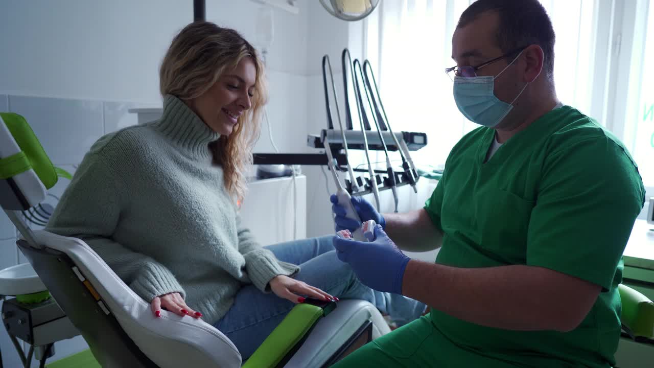 男牙医利用模型教女病人如何正确刷牙视频素材