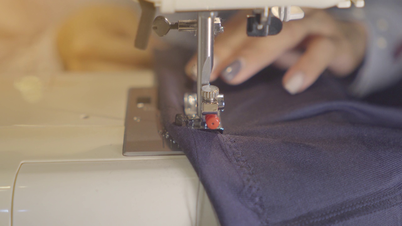 女性手拿牛仔布在缝纫机上，特写镜头。衣物维修、回收利用、家居爱好和家居工作的概念。视频下载