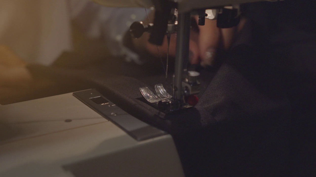 女性手拿牛仔布在缝纫机上，特写镜头。衣物维修、回收利用、家居爱好和家居工作的概念。视频下载