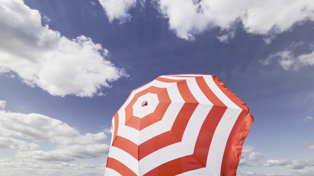 红白条纹阳伞在夏日迎风翻飞视频下载