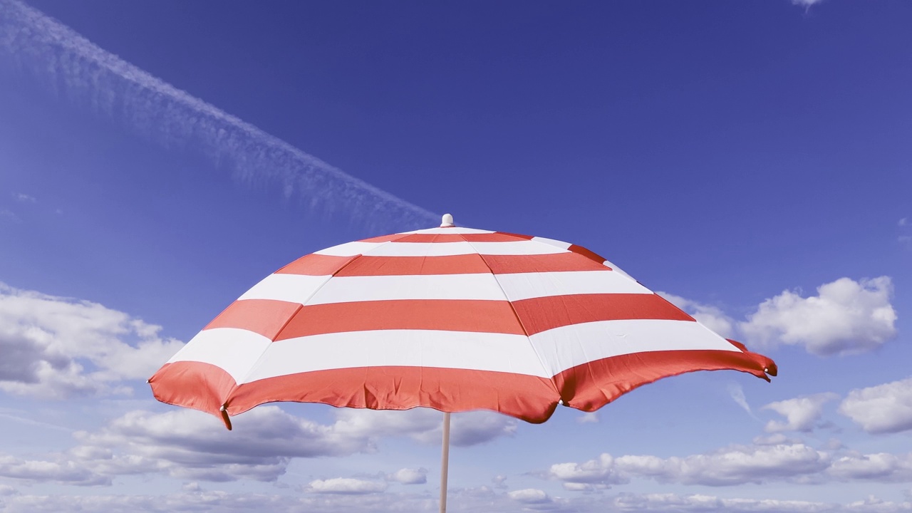 红白相间的阳伞在夏日迎风而动视频下载