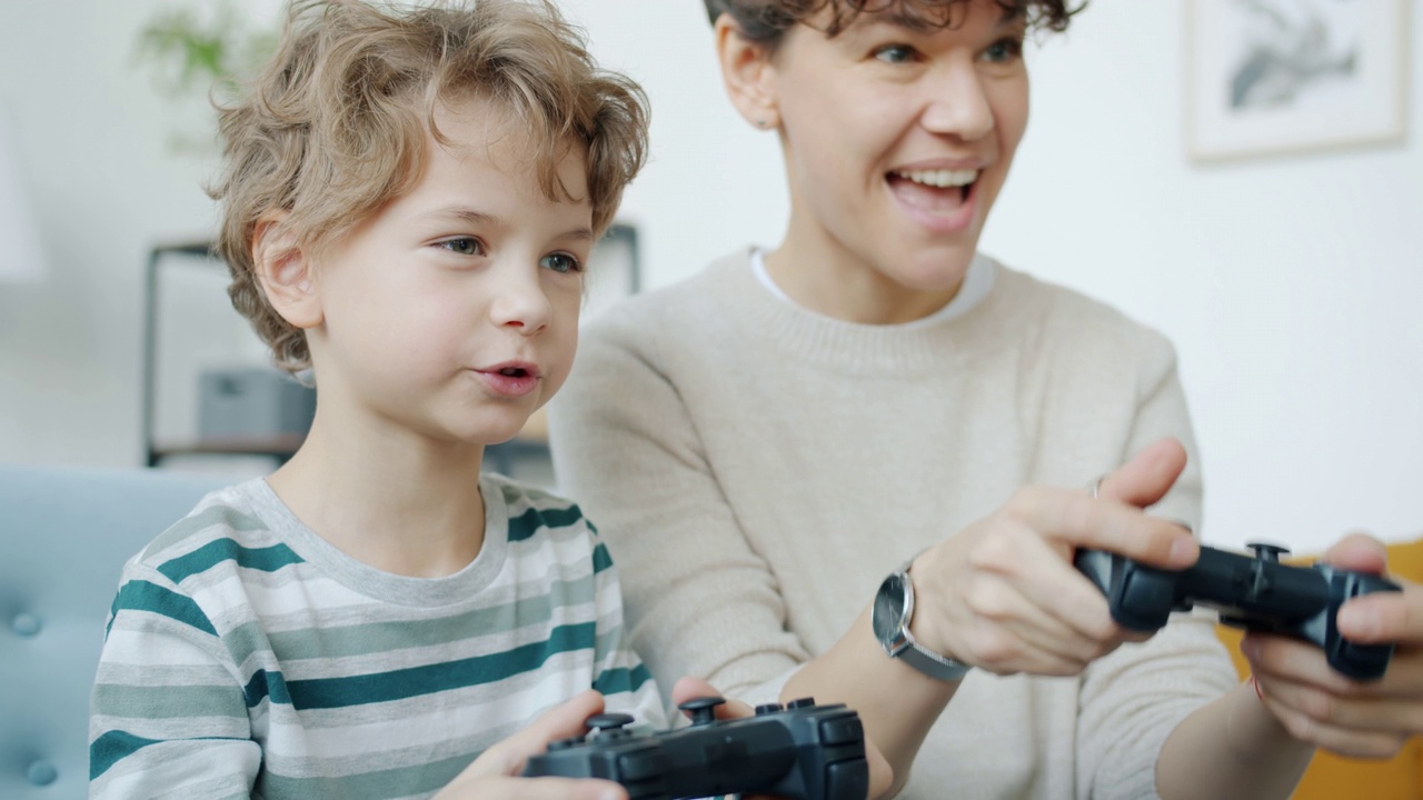 家里妈妈和孩子玩电子游戏击掌拥抱的慢镜头视频素材