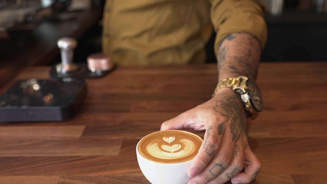 咖啡师提供的拿铁咖啡用泡沫牛奶装饰成心形视频下载