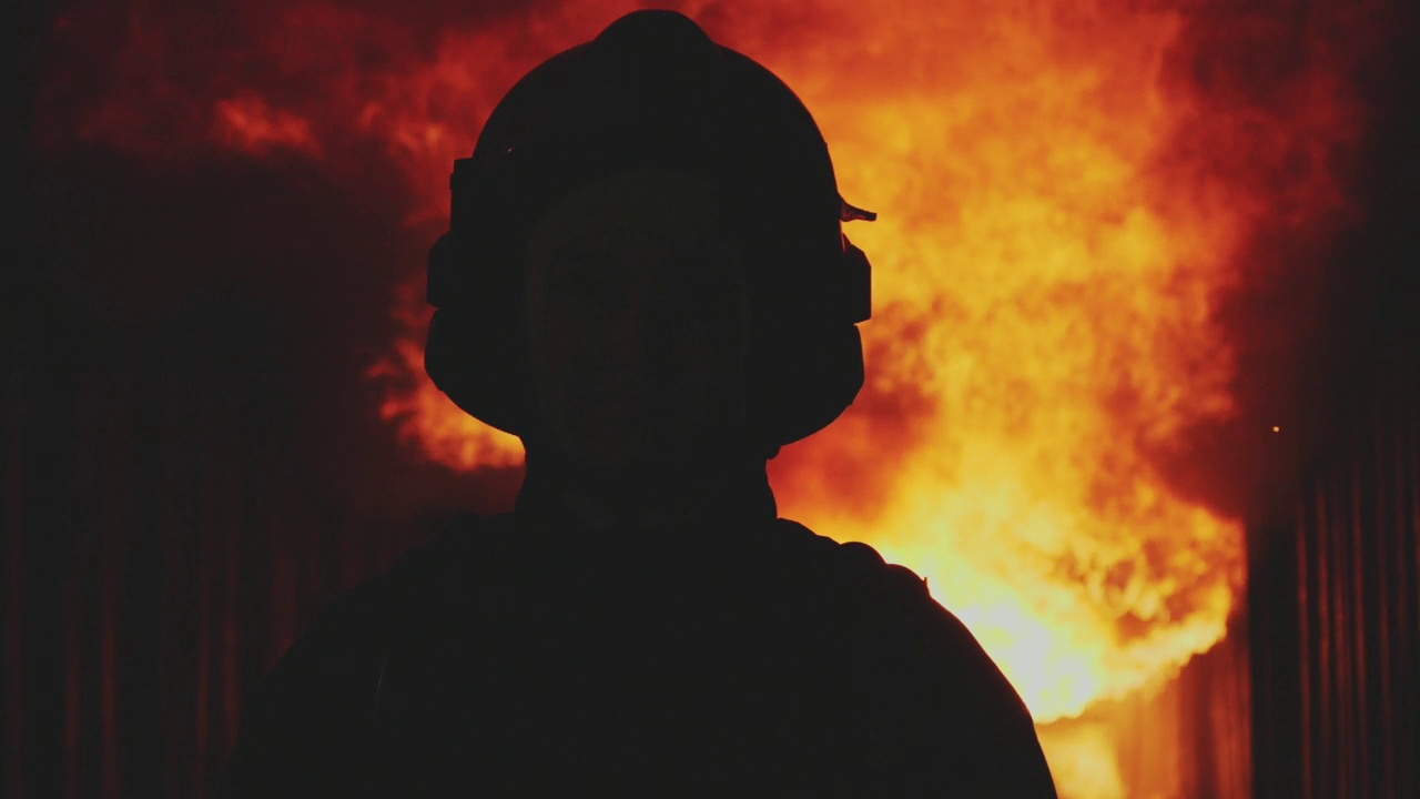超级慢镜头的消防员走向镜头，背景是熊熊大火。视频下载
