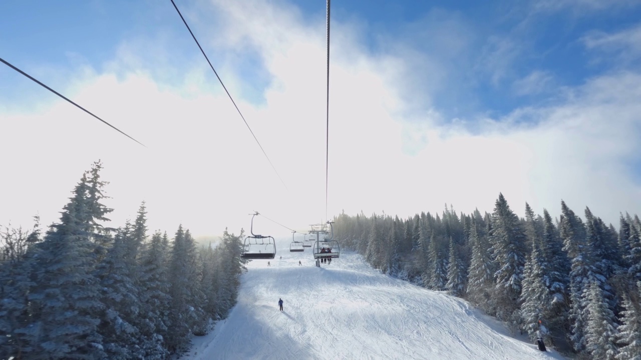 从滑雪椅升降机和雪炮喷洒人工雪在滑雪坡和树木的POV视频素材
