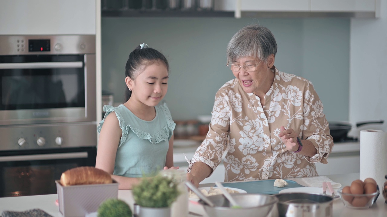 亚裔华人老太太周末在厨房展示和教她的孙女煮饺子视频下载