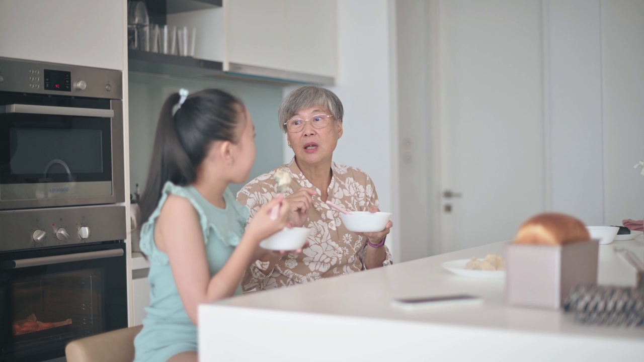 亚裔华人老太太和她的孙女在厨房的柜台上吃饺子视频下载