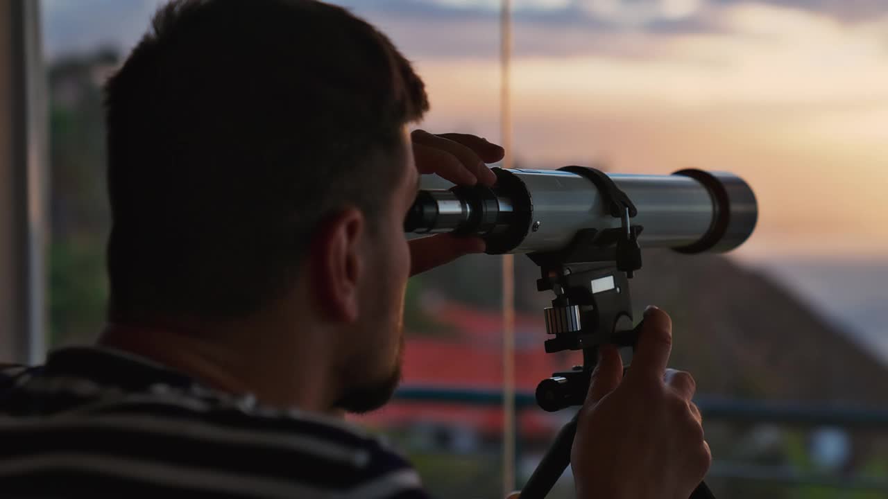 男子在露台上欣赏风景。通过望远镜看到的全景。前景聚焦视频下载