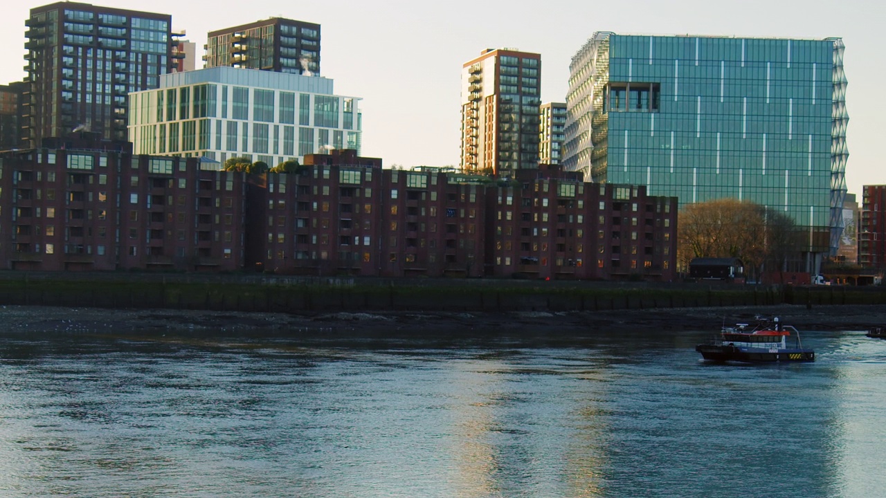 伦敦泰晤士河上的一艘船，背景是一座城市建筑。视频下载