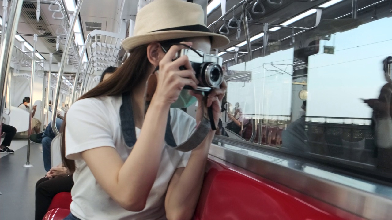 女摄影师在旅游列车上旅行，运输在一个郊区。视频下载