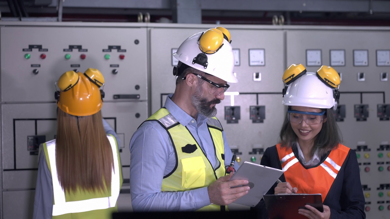 专业工程师戴着头盔在工厂控制设备面板上工作。视频素材