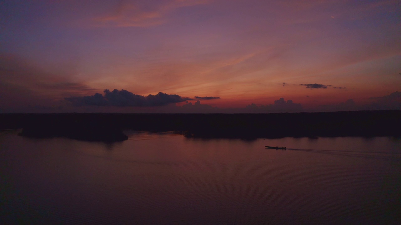 一艘摩托艇在美丽的夜空下驶过一条小河视频素材