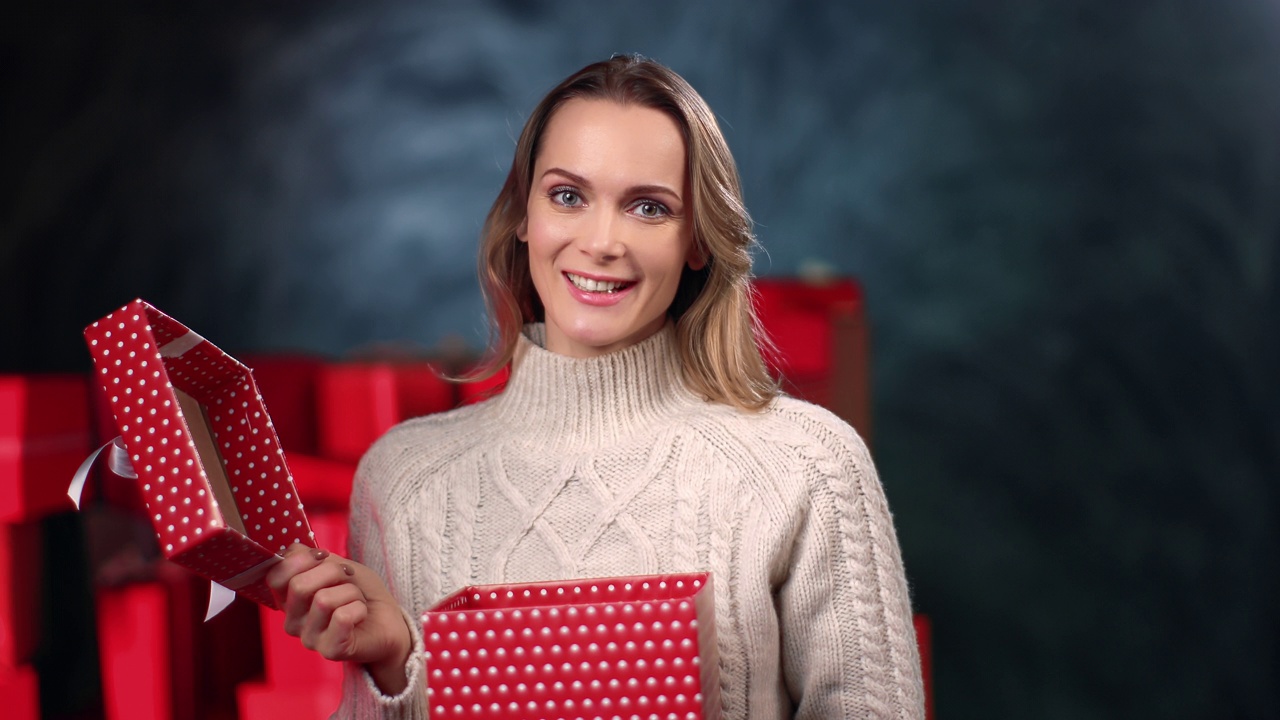 肖像女子打开节日红色包装礼盒微笑积极的情绪在灰色工作室摆姿势视频下载