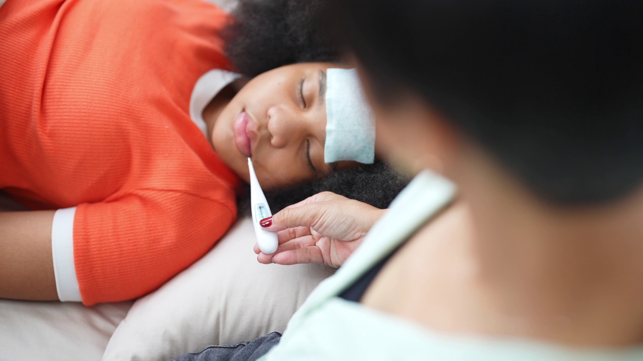 4K非洲母亲用数字温度计检查卧病在床的女儿的体温视频素材