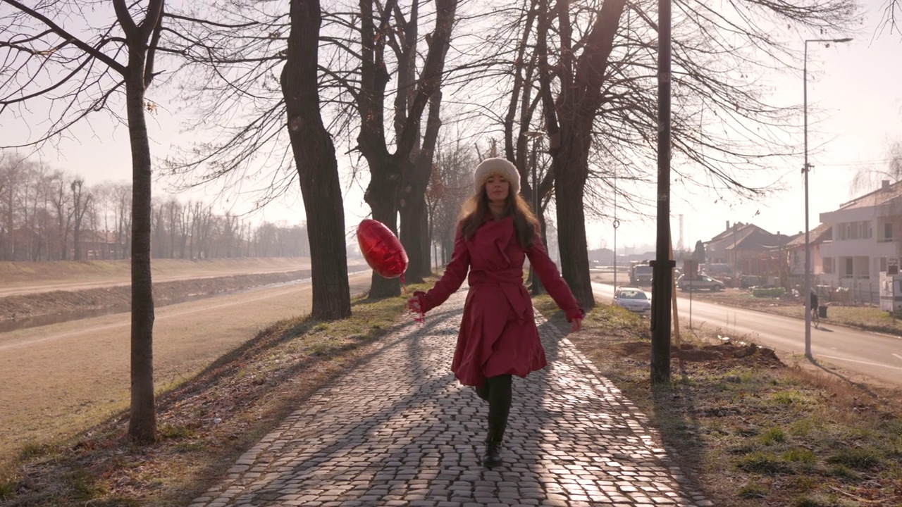 一个女人拿着一个心形的热气球在跳视频下载