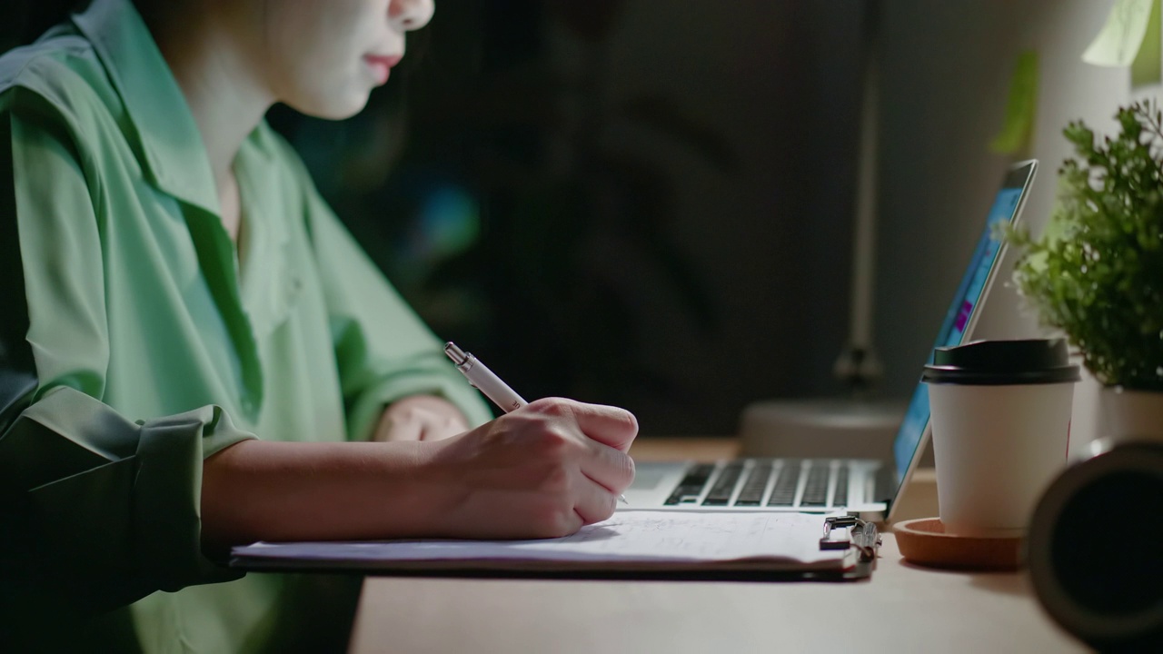 一个女人在晚上用笔记本电脑学习电子学习视频素材