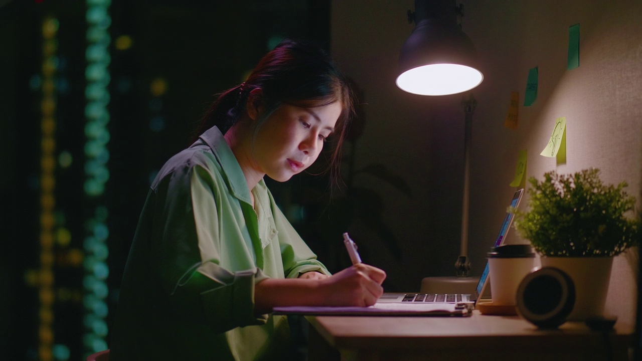 一个女人在晚上用笔记本电脑学习电子学习视频素材