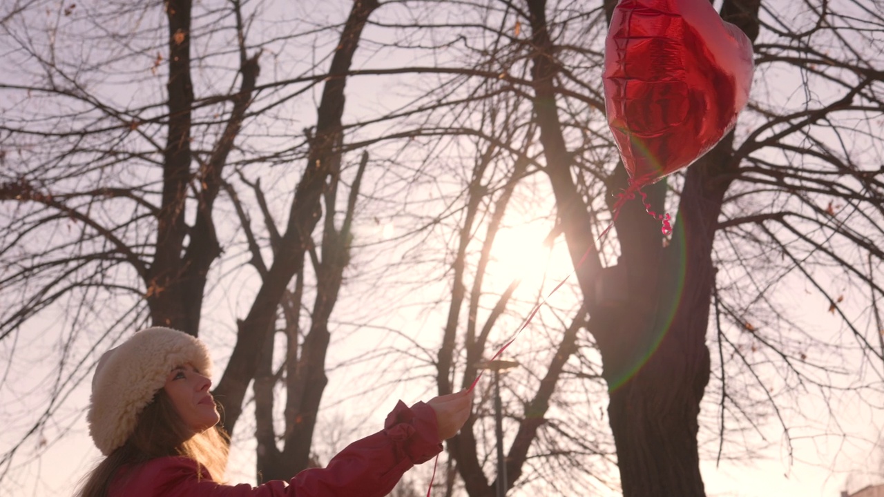 女人向空中释放心脏气球视频下载