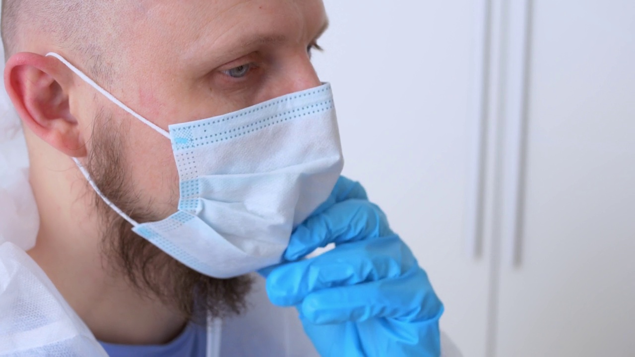 特写镜头:一名在传染病科换班的医务人员脱下防护服、护目镜、口罩和手套。与冠状病毒患者一起工作后疲惫的医生视频素材
