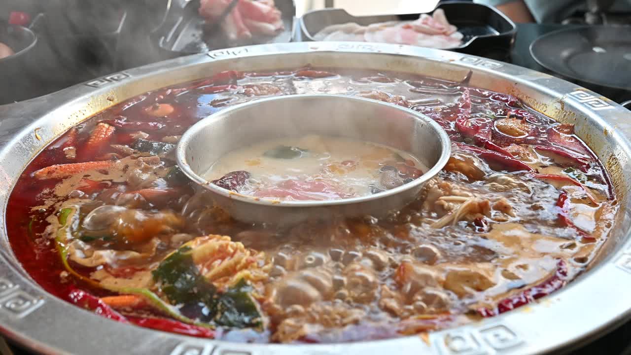 人们用筷子将肉放入辛辣的中国火锅的特写。视频素材