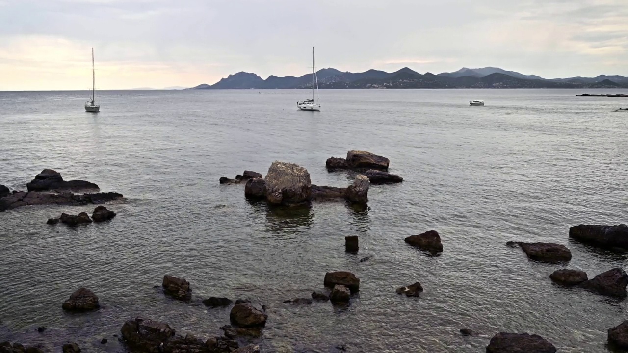 俯瞰地中海岩石海岸的圣玛格丽特岛，小船，远处的小镇，法国视频素材
