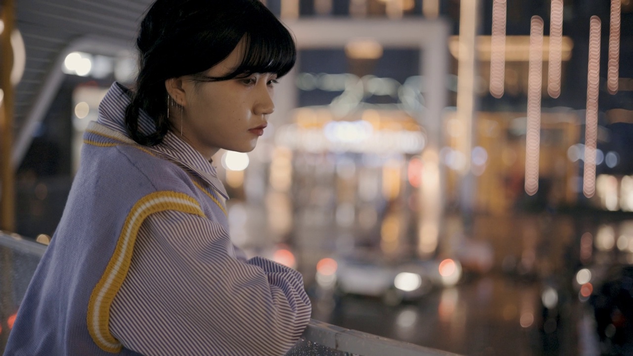 一幅年轻女子的肖像，在夜晚的城市霓虹灯的照耀下。视频素材
