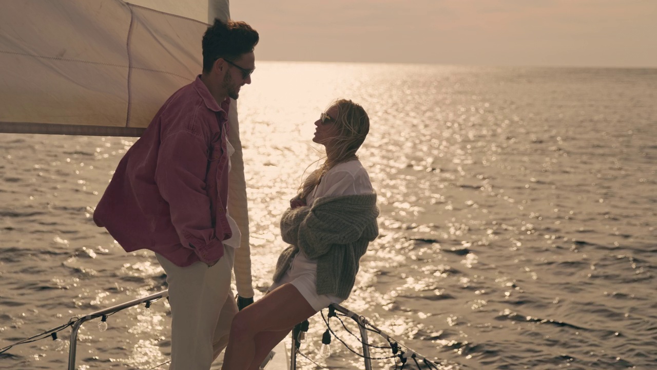 日落时分，一对年轻的夫妇在一艘帆船的甲板上畅谈视频下载