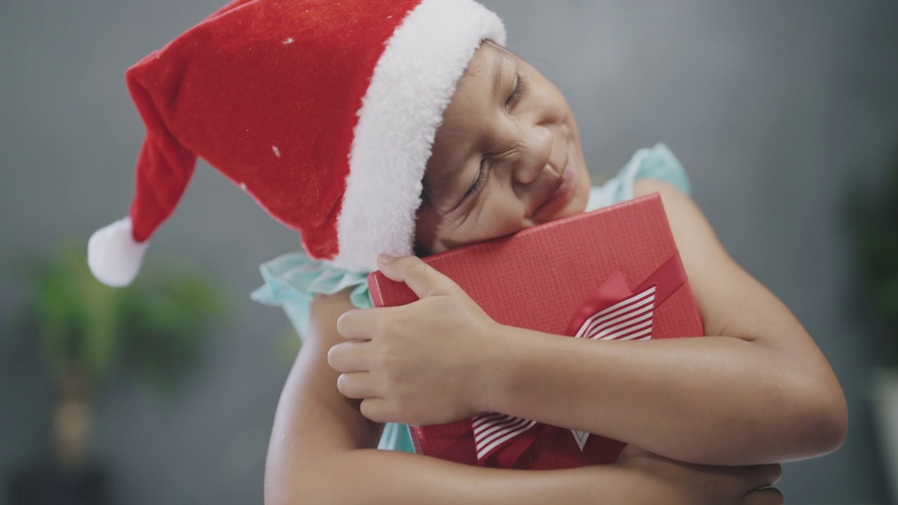 戴圣诞老人帽子的小女孩得到空的礼品盒。视频下载