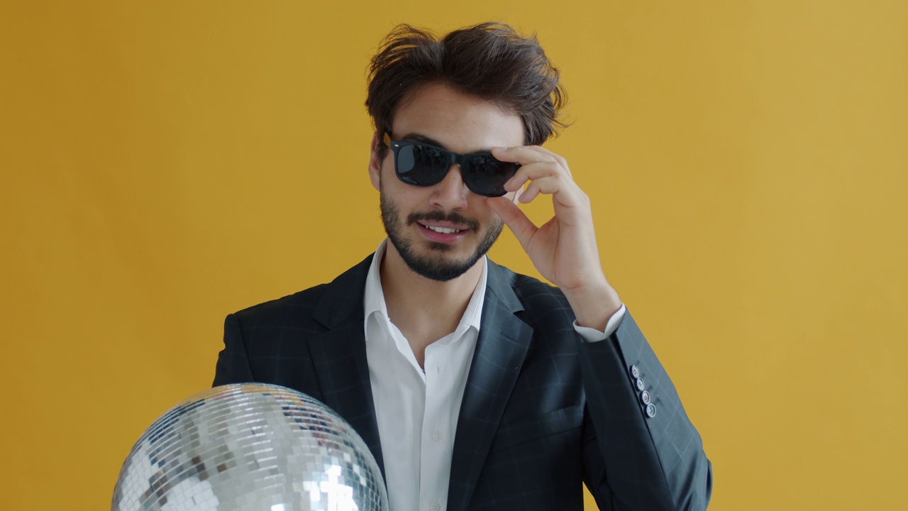 吸引人的中东男人的肖像，拿着迪斯科球固定太阳镜视频素材