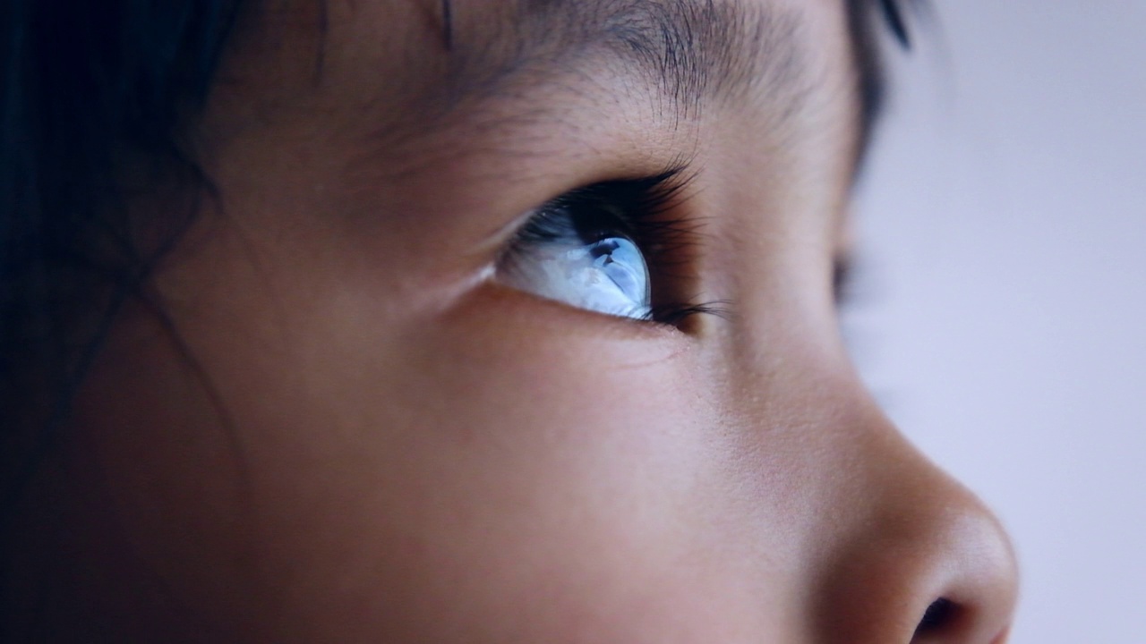 亚洲小孩仰望天空的特写。美丽的棕色眼睛，长长的睫毛。视频下载