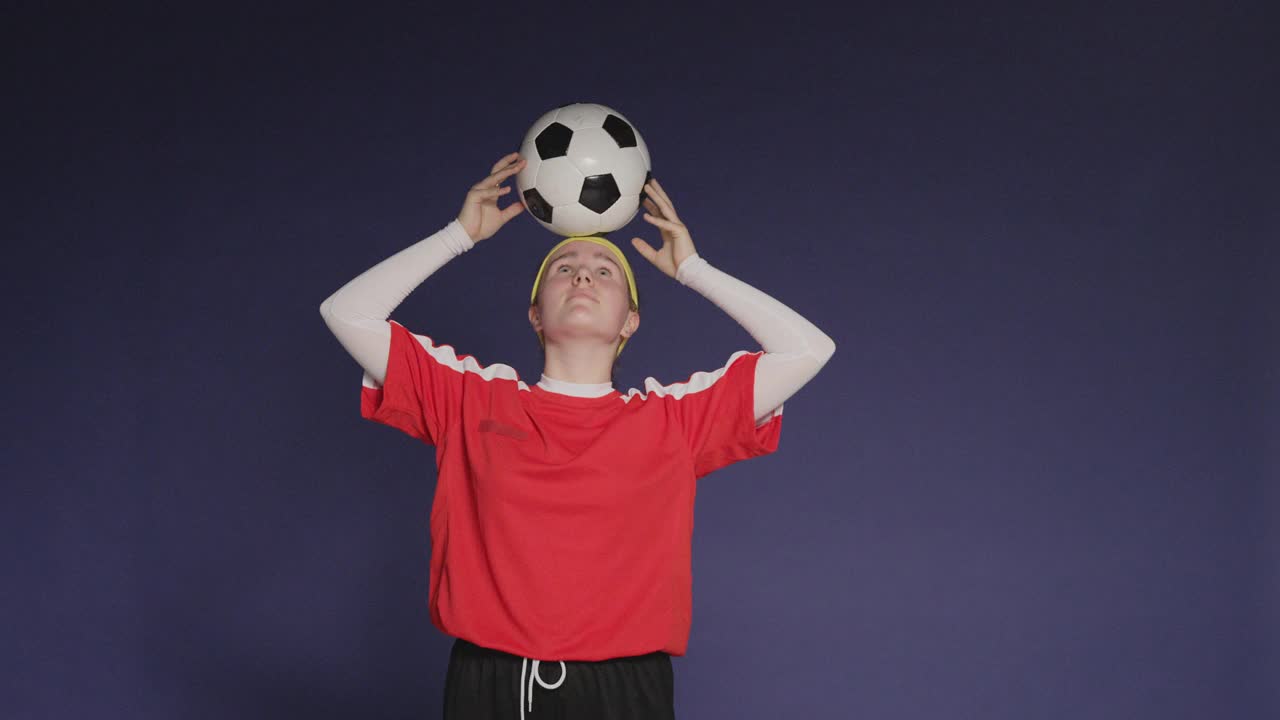工作室拍摄了一个十几岁的女孩用前额平衡足球的镜头视频下载