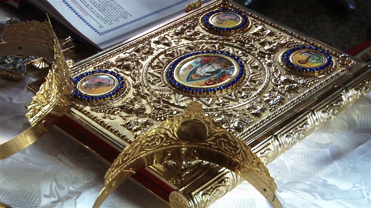 新郎的金属王冠和结婚戒指放在圣坛的圣书上视频下载