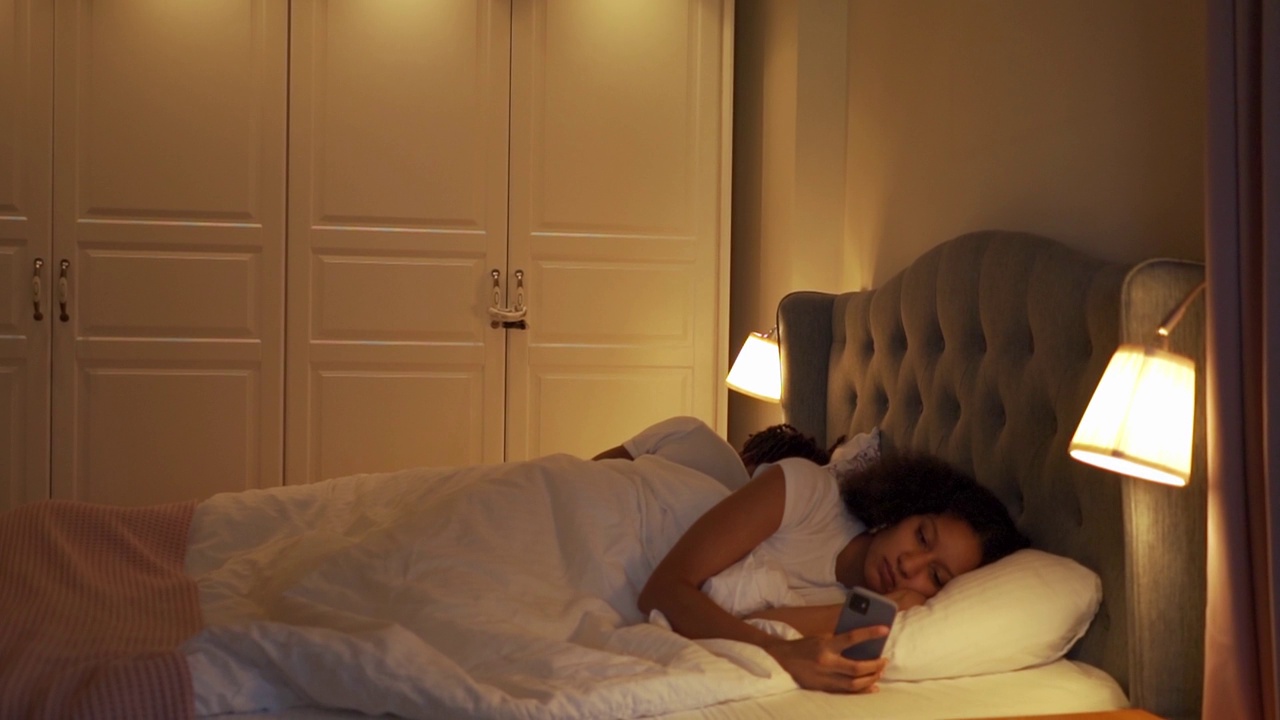 一个失眠症的女人在床上看她的手机视频下载