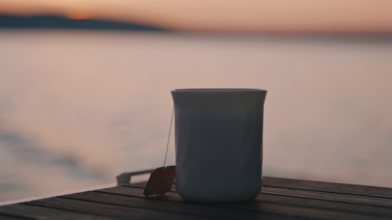 黄昏时分，白色杯子放在帆船的木制船尾上视频素材