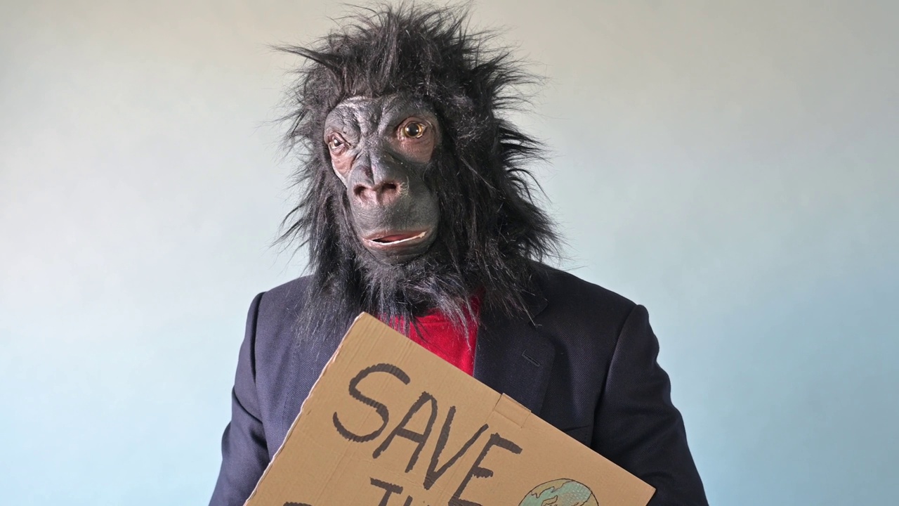 一名男子戴着大猩猩面具，举着一个牌子，上面写着“拯救地球”。视频下载