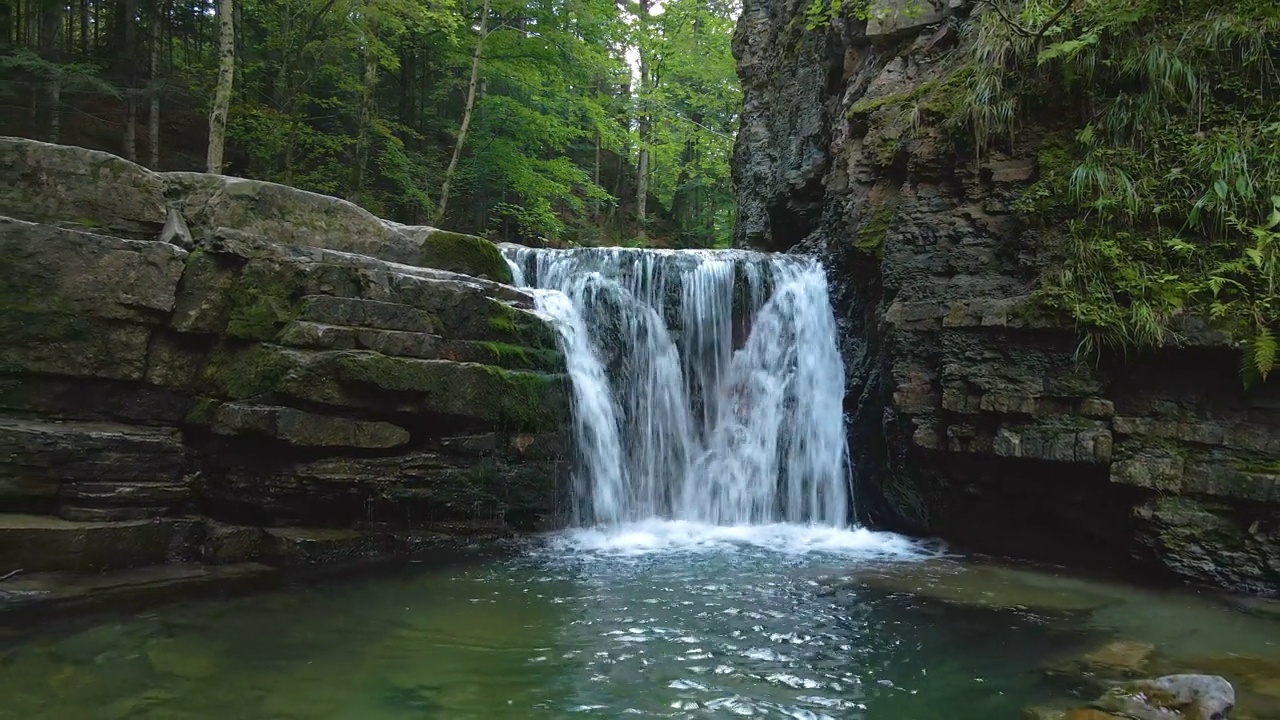 在夏季的森林里，山河上的瀑布，白色的泡沫水从岩石中落下视频素材