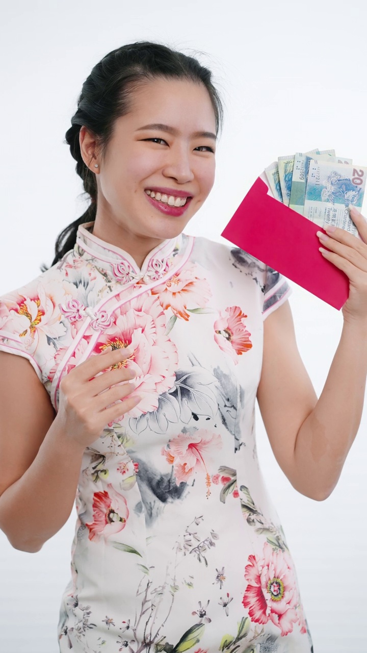 中国/亚洲妇女穿着旗袍，白色花卉图案的衣服，手拿红色的钞票给她的家人，亲戚和朋友，祝新年快乐，富有，幸福，和幸运视频下载