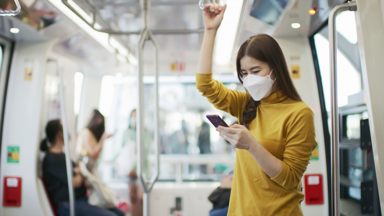 年轻的亚洲女性戴着医用口罩乘坐火车乘坐公共交通工具视频素材
