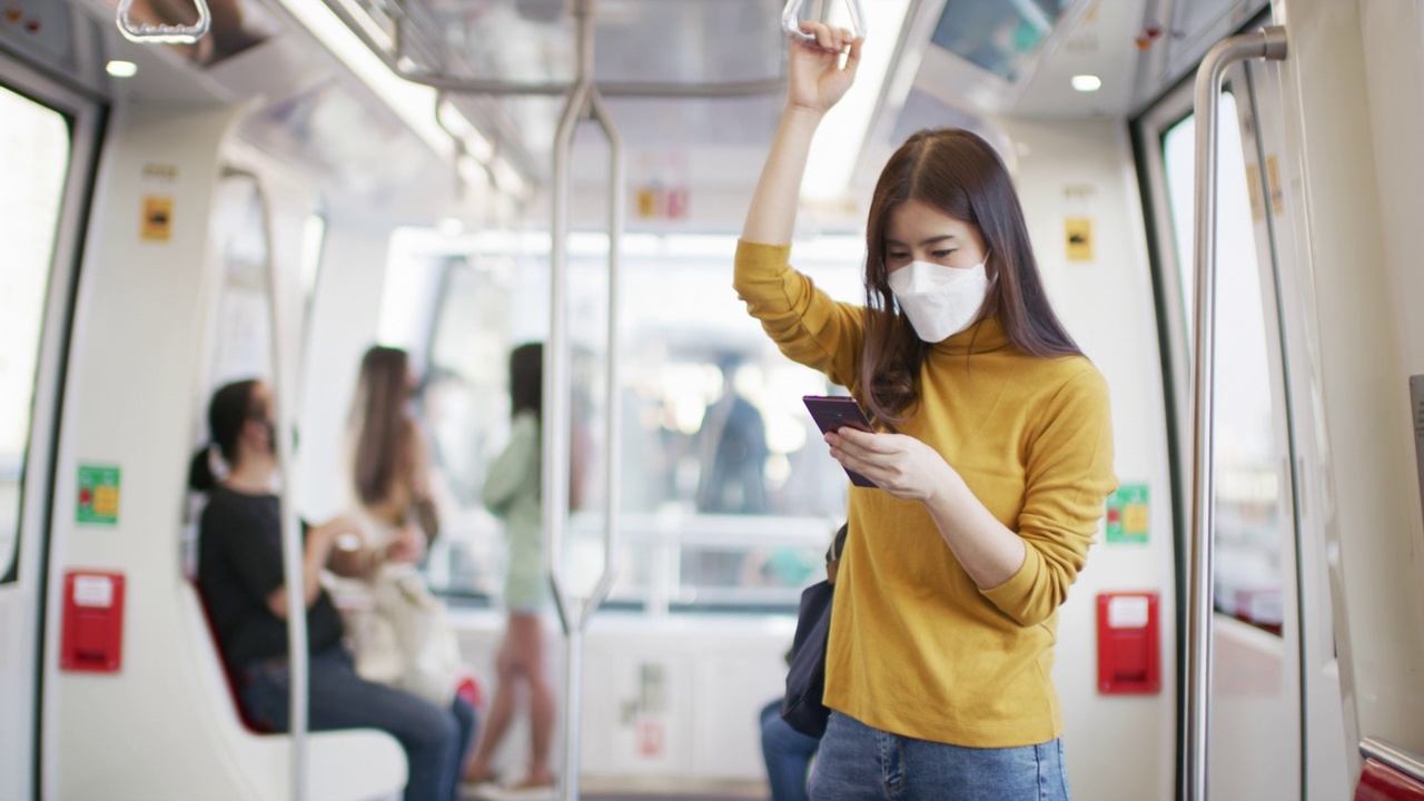 年轻的亚洲女性戴着医用口罩乘坐火车乘坐公共交通工具视频素材