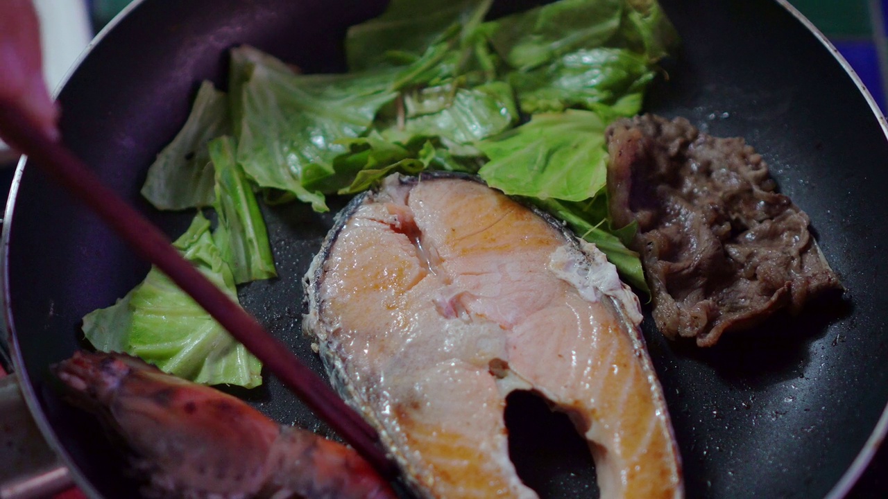 将鲑鱼、虾、蔬菜和肉放在热盘上烤。视频素材