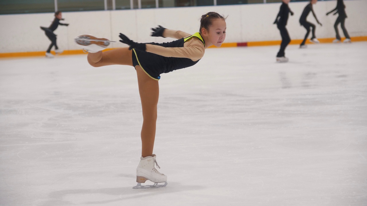 一个小女孩在公共溜冰场练习花样滑冰，现场表演旋转视频下载