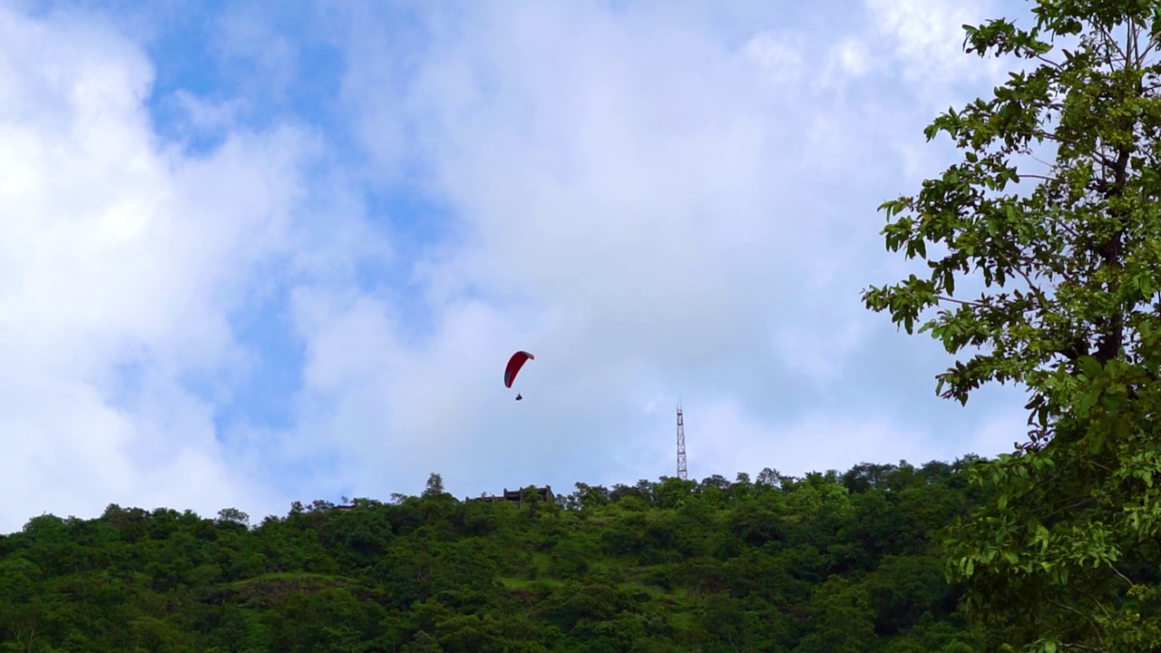 在印度古吉拉特邦的萨普特拉，游客们在山上享受滑翔伞。游客在萨普特拉体验冒险活动。在蓝天白云前跳伞。视频素材