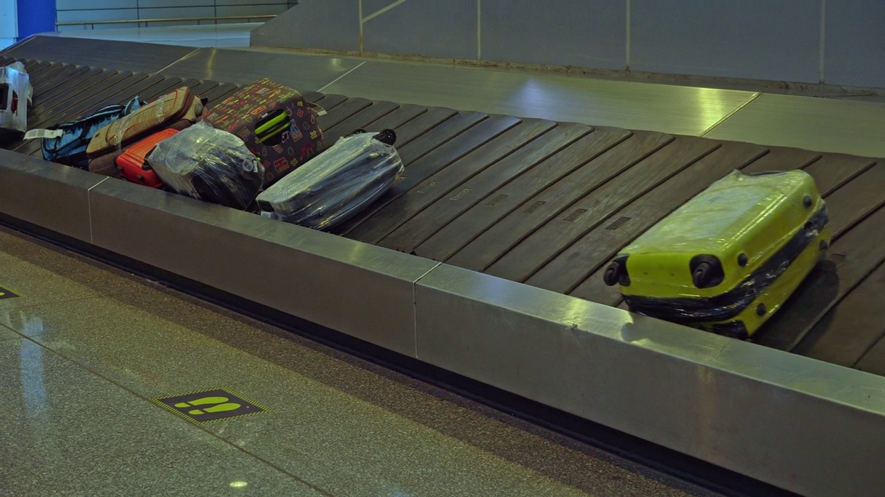 行李放在机场的行李传送带上。下飞机后，行李箱在胶带上旋转。视频下载