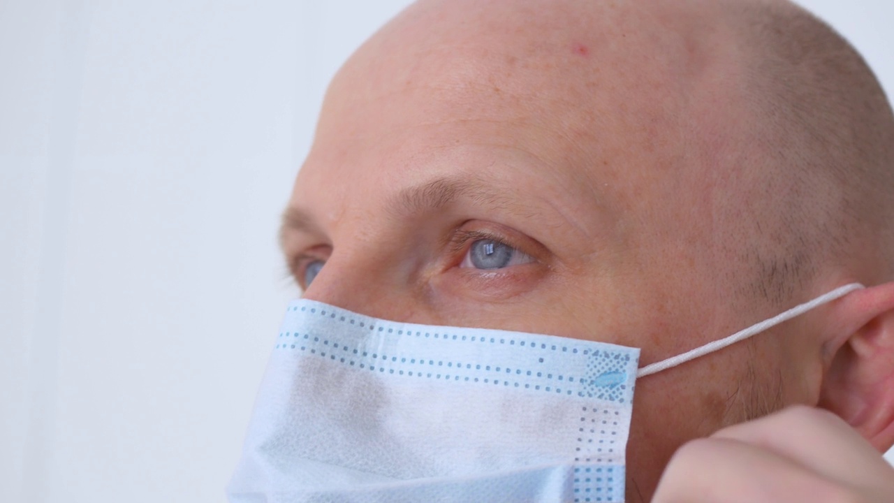 外科手术成功后摘掉眼镜的医生的脸部特写。在冠状病毒感染地区工作后，卫生工作者会脱去长袍和口罩视频素材