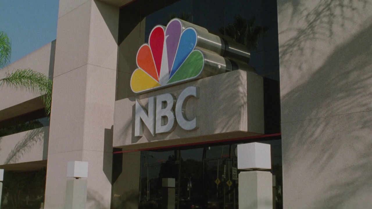 潘文石从街道与汽车从左到右到NBC大厦入口。NBC标志和孔雀标志。视频下载